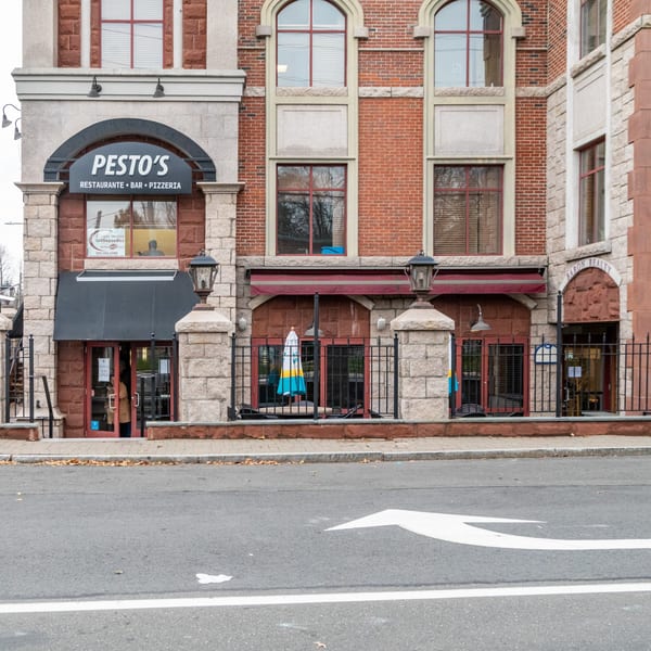 Cafe Pesto's Italian restaurant exterior with a black awning and outdoor seating.